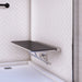 Metlam folding accessible shower seat in black laminate installed in a commercial shower — demonstrating space saving and accessibility.